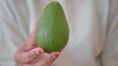 una mano sosteniendo un aguacate maduro