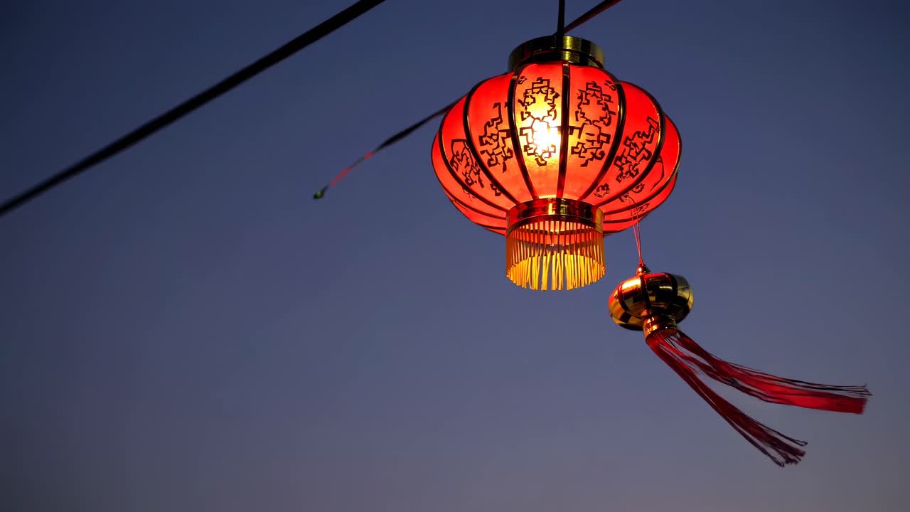 Low-angle shot of a glowing red lantern against a twilight sky, capturing a serene and festive
