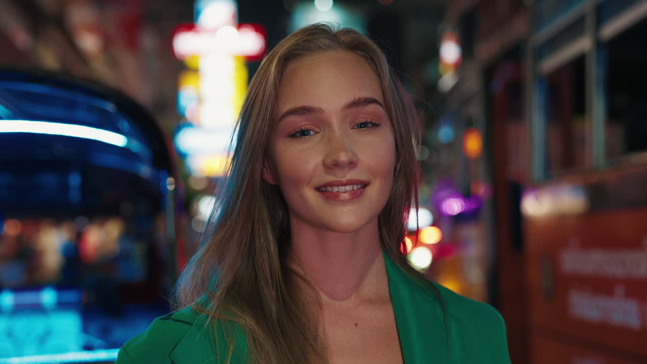 Mujer sonriente en una calle de ciudad por la noche