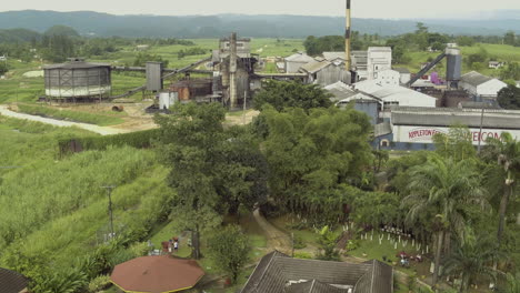 Aerial-view-of-the-Appleton-rum-estate-rising-up-to-reveal-the-signage-on-the-building-and-expanse-and-scale-of-the-site-and-a-flock-of-birds-fly-into-shot-below