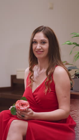 mujer coqueteando posa para el artista en el estudio. mujer seductora en vestido de hendidura roja sostiene rosa inspirador pintor para dibujar en la tienda de arte. modelo en vivo para el maestro