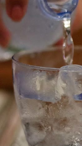 water being poured into a glass with ice