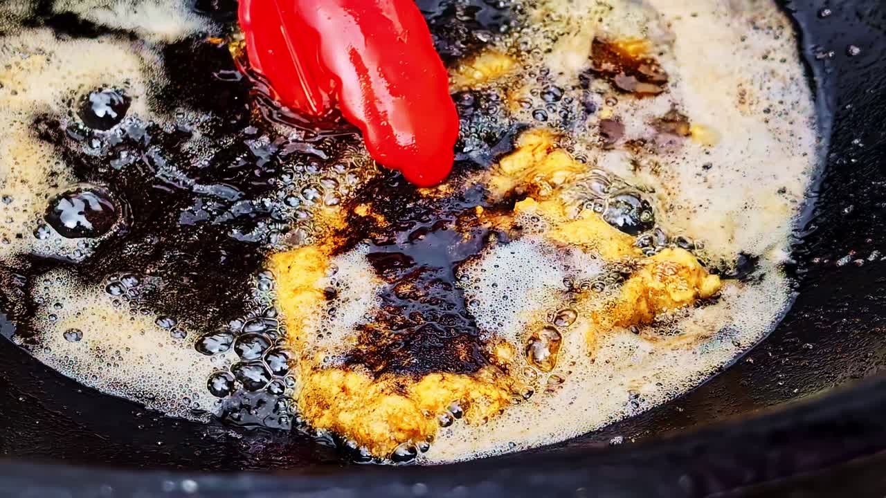 Oil bubbles as fresh fish fillet sizzles in pan and spatula flips it over repeatedly