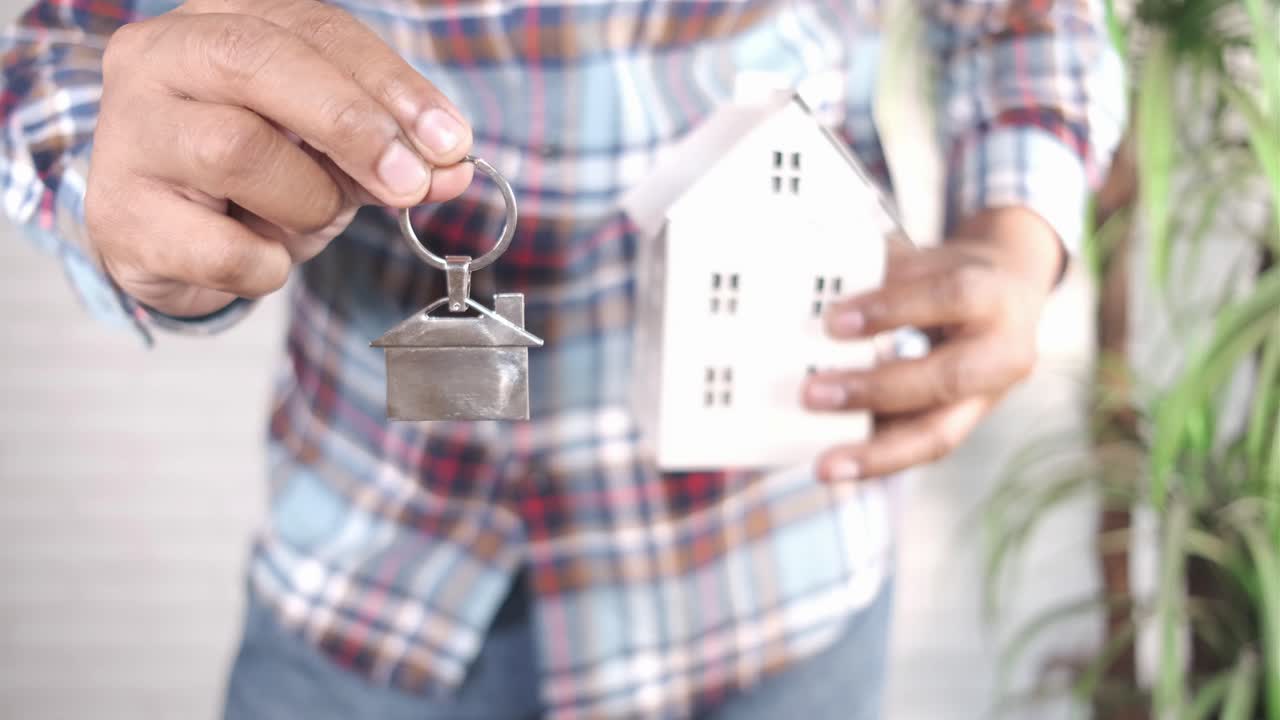 hombre con llaves de la casa y un modelo de casa