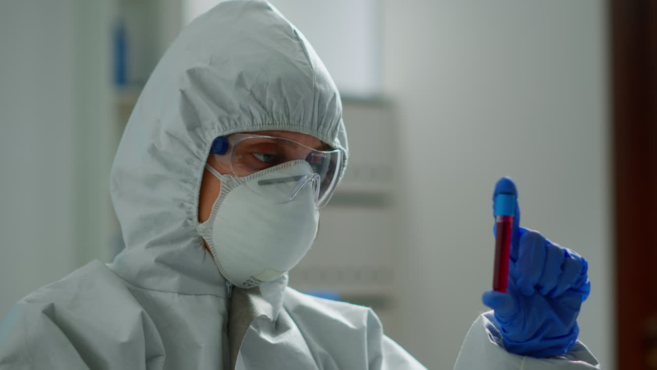 Scienziato in tuta protettiva che fa ricerca analizzando un liquido in provetta