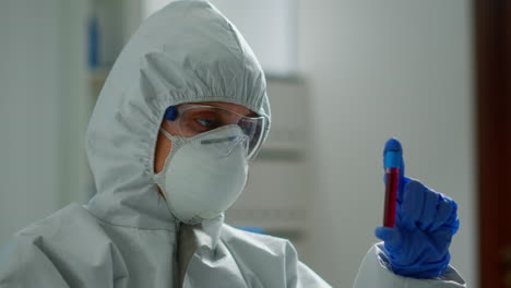 scientist in coverall doing research analysing liquid in tube