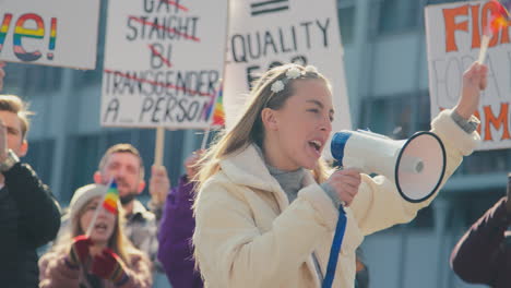 group of protestor with megaphone waving flags on demonstration march for gender equality