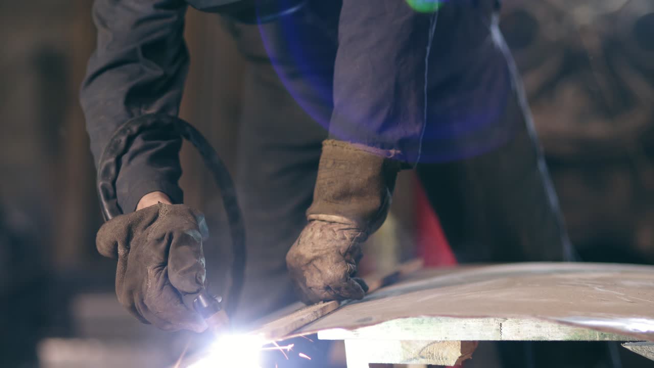 Hands of a workman in protective gloves holding wood plank to adjust a cutting line on metal construction. Cutting with metal oxy