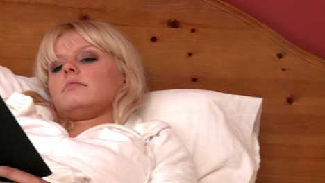 peaceful woman lying on bed reading a book