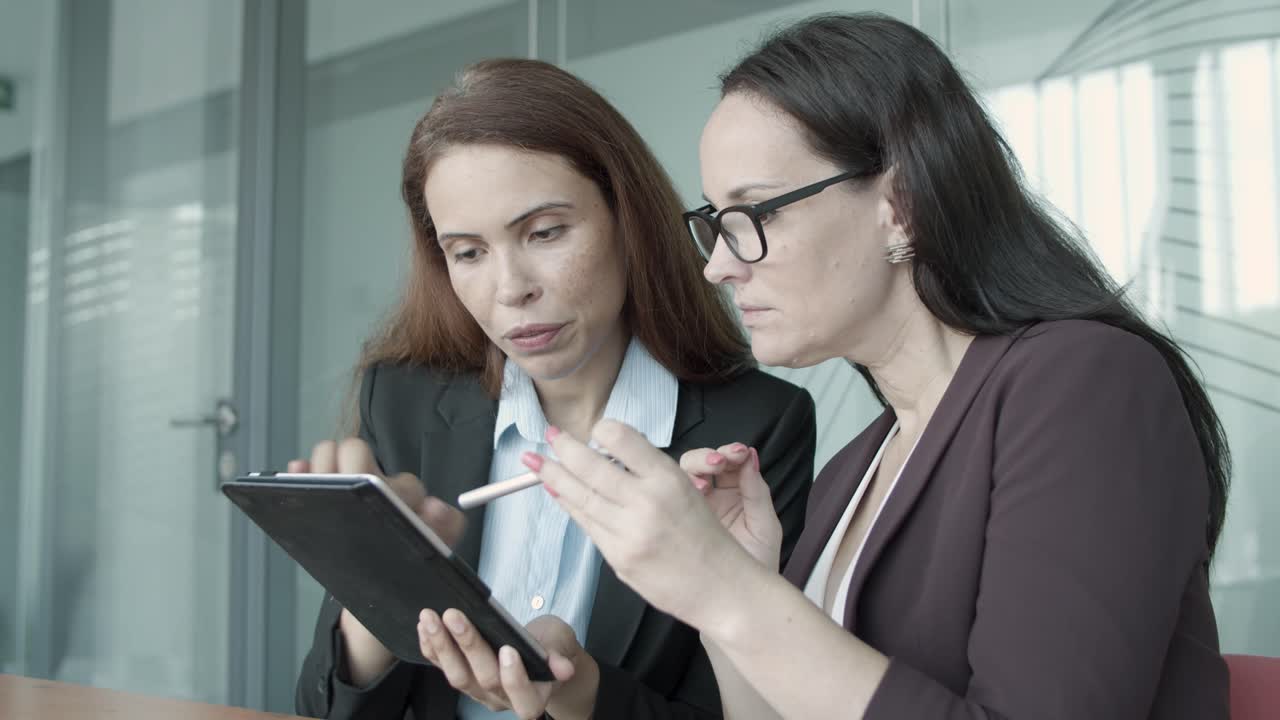 jóvenes mujeres de negocios bonitas viendo el proyecto a través de la tableta