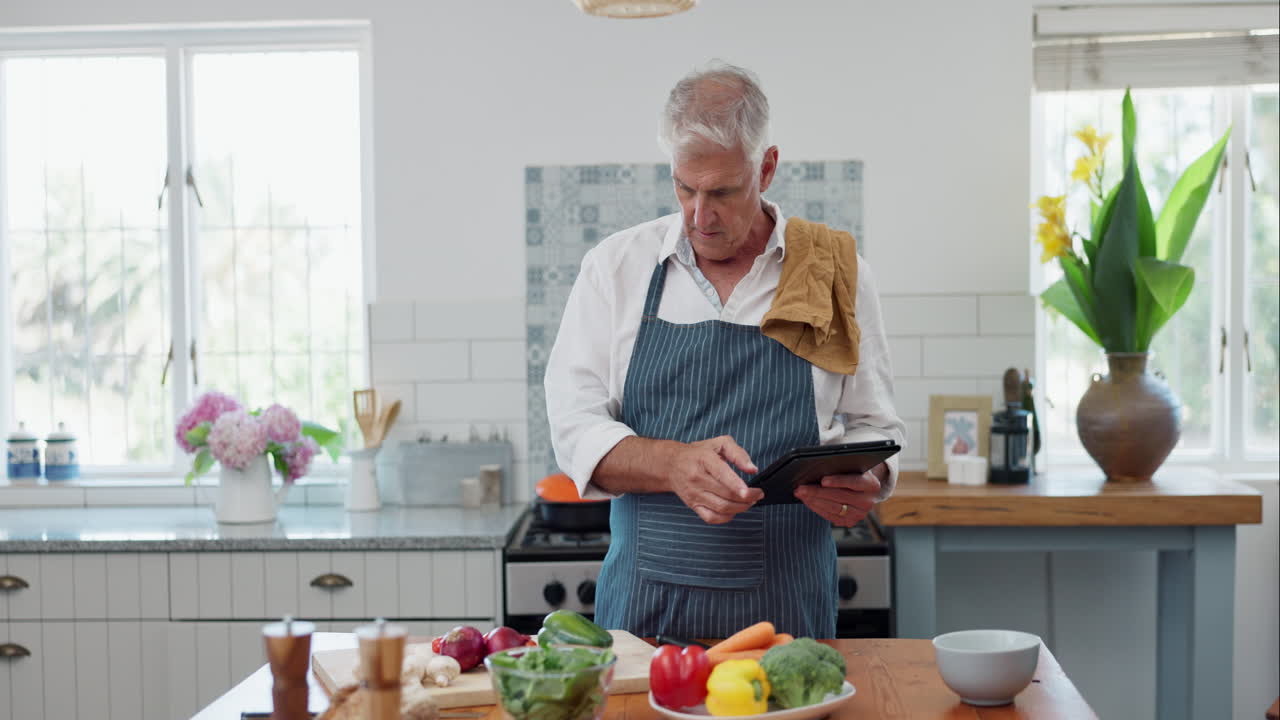 hombre mayor siguiendo la receta en línea en la cocina