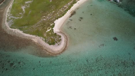 Aerial-tilt-up-view-of-Cayo-de-Agua-in-Los-Roques,-showcasing-the-coral-barrier-and-turquoise-sea