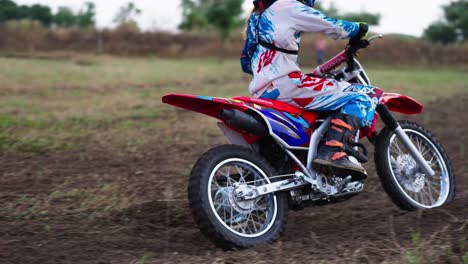 girl on motocross bike racing on dirt off-road track in slow motion during competition - tracking shot