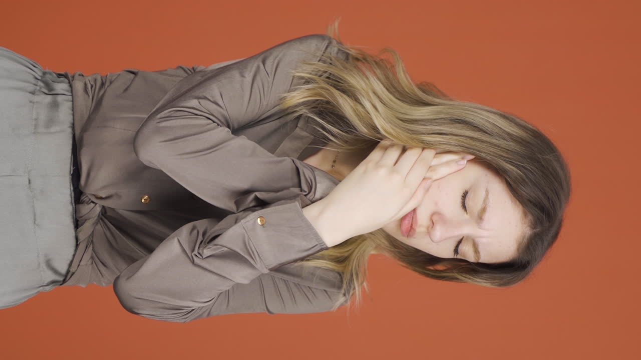 치통을  ⁇ 고 있는 젊은 여성의 수직 비디오.