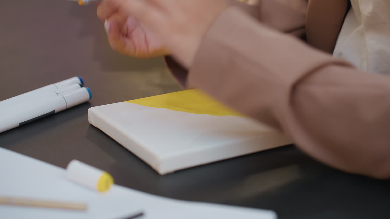 Diseñador realizando bocetos conceptuales rápidos, movimientos rápidos de las manos planificando componentes visuales en un lienzo brillante, artista organizando rápidamente ideas a través de bocetos a rotulador sobre un alegre fondo amarillo.