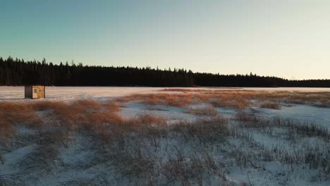 Slow-moving-drone-shot-of-ice-fishing-cabin-in-snowy-British-Columbia-landscape