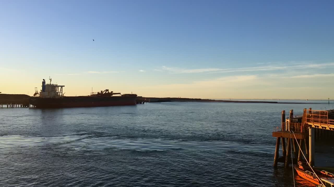 timelapse de remolcadores moviéndose cerca de un muelle durante una puesta de sol en un día claro