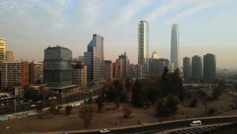 Aerial-view-passing-above-a-highway-with-the-city-and-skyscrapers-as-background-in-Chile