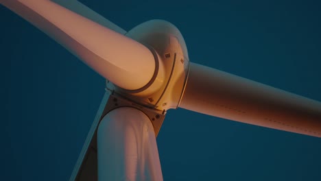 close-up of a wind turbine blade turning against a blue evening sky