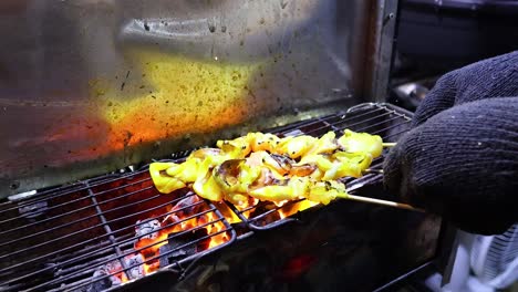 hand grilling squid skewers over open flames