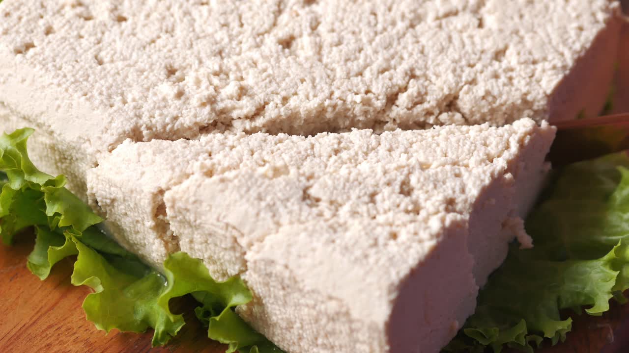 Vista dall'alto di mani che tagliano il tofu con un coltello