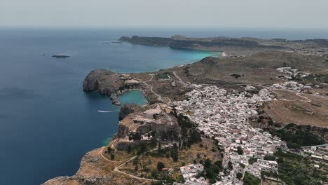 Whitewashed-village-in-Lindos-and-tAcropolis,-landmark-of-Rhodes-on-Aegean-Sea,-Aeriall-view