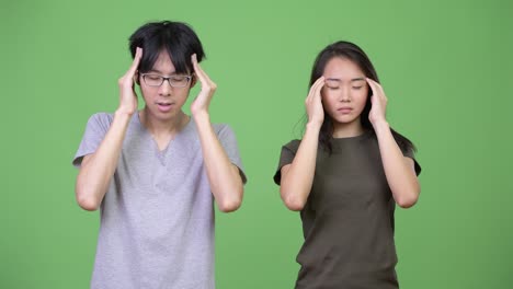 젊은 아시아 커플이 함께 두통을 고 있습니다.