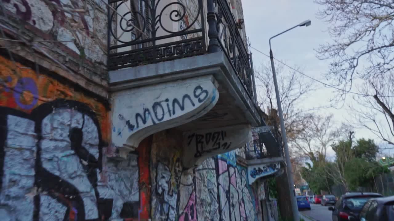 Handheld walking shot of old abandoned building with graffiti oart on the exterior, located at Kifissia, Greece