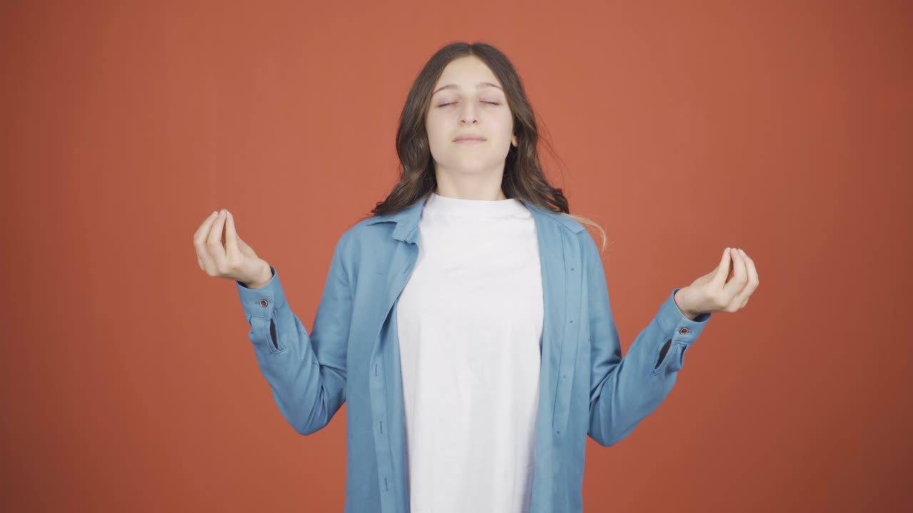 카메라를 쳐다보며 명상하는 젊은 여성.