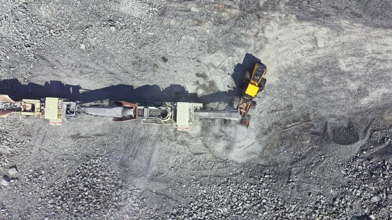 Granite quarry in operation with machines processing stone and moving material during daytime work hours