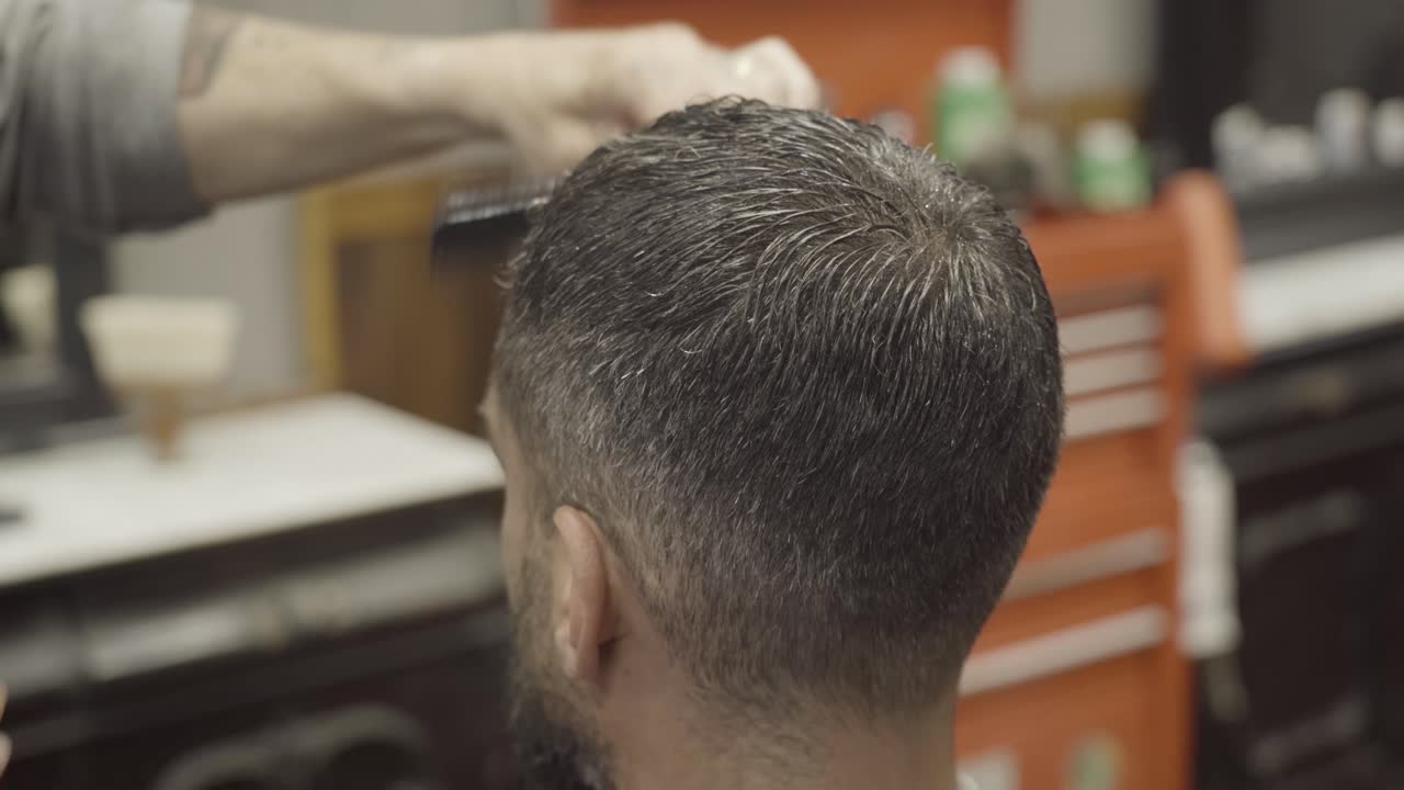 Stilista che spruzza acqua sui capelli del cliente in una barberia.