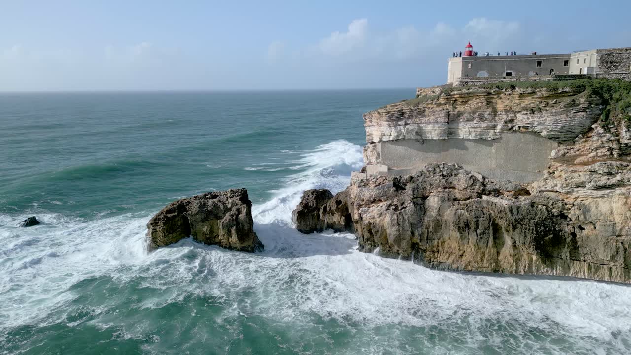 vista impresionante del faro de nazare en la cima del acantilado con las olas del océano salpicando la costa rocosa en portugal