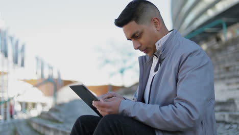 Cheerful middle eastern young man using modern tablet