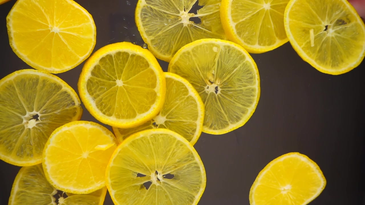 Fette di limoni cadono su una superficie trasparente. Vista dal basso. Rallentatore