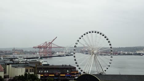 beautiful shot of the seattle marina with the famous ferris wheel during an overcast cloudy day with a large port in the background in washington state, usa