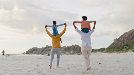 niños en los hombros de los padres en la playa y vista de atrás