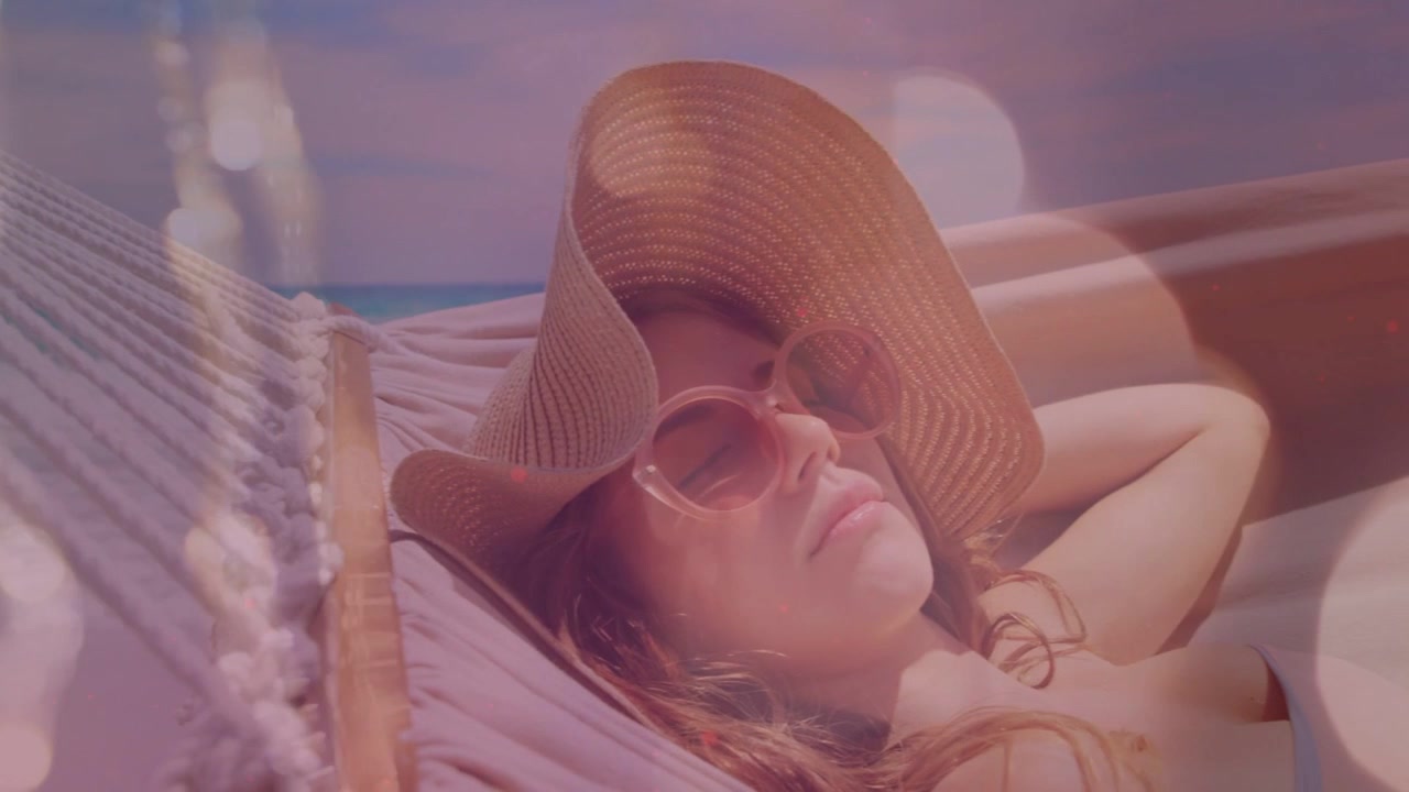 Camera zooming out, woman resting in hammock with straw hat, bokeh floating over teal sea, travel
