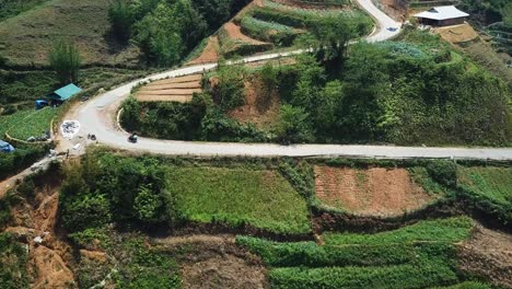 Eine-Luftaufnahme-Folgt-Einem-Motorrad-Eine-Kurvenreiche-Straße-Hinauf-Durch-Terrassierte-Felder-In-Richtung-Der-Spitze-Eines-Hügels