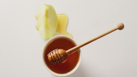 video of honey in jar and apple slices lying on white surface