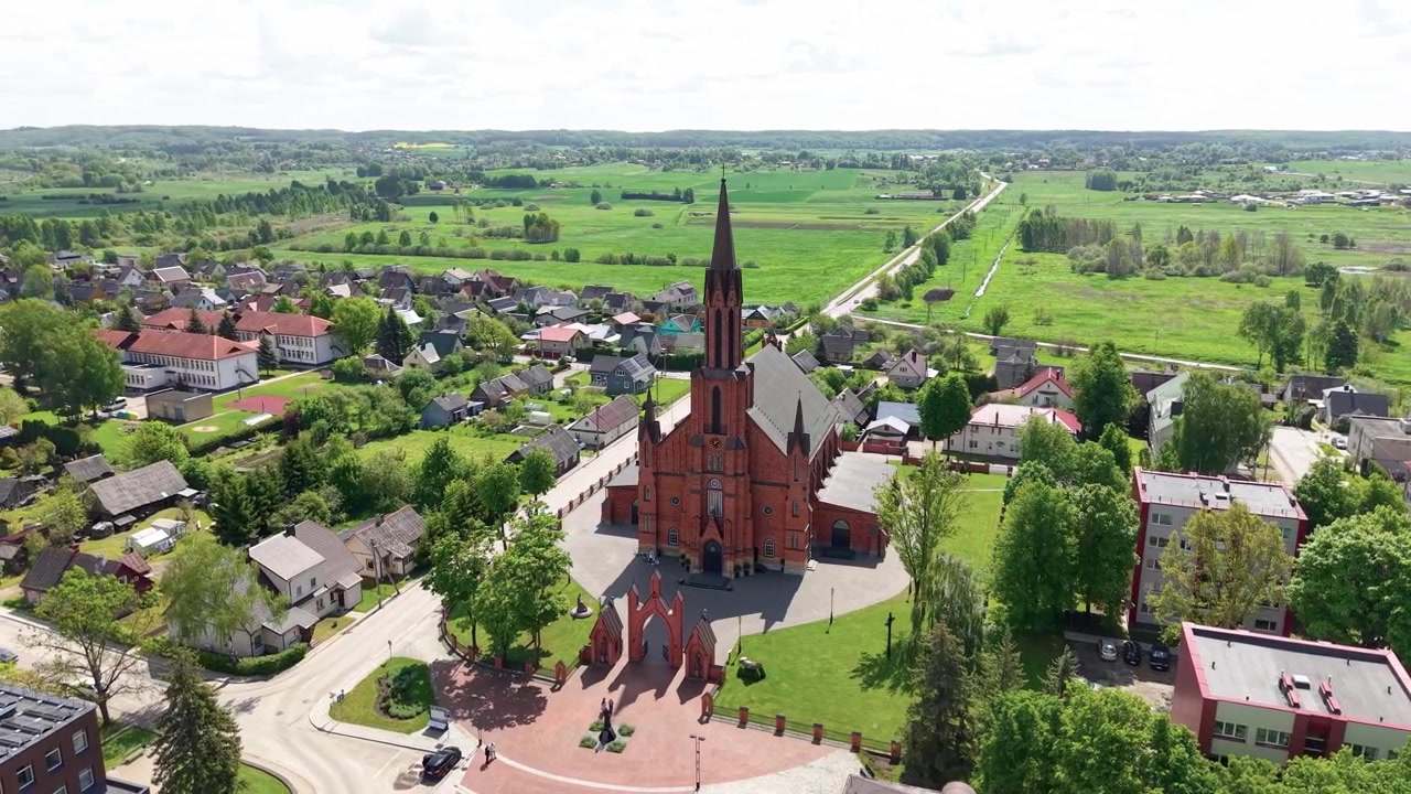 Splendido video drone che mostra la sorprendente architettura in mattoni rossi della Cattedrale di Kaišiadorys, la vegetazione lussureggiante e le affascinanti strade di una piccola città in pieno giorno. Riprese aeree, grandangolo.