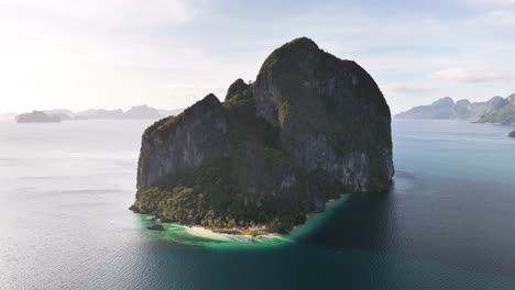 drone orbiting pinagbuyutan island in el nido, palawan, revealing dramatic limestone formations, dense foliage, and turquoise waters of the bacuit bay in the sulu sea
