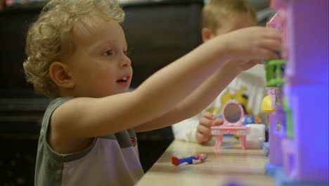 kleine jongens spelen met speelgoedhuis thuis