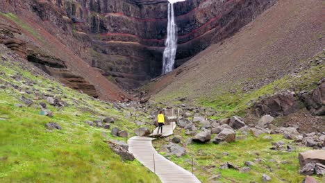 mujer caminando hacia una hermosa cascada en islandia