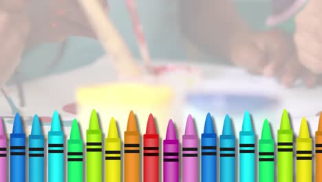 Multiple-colored-crayons-against-mid-section-of-kids-painting