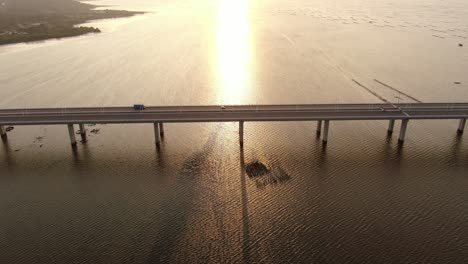 Traffic-on-Hong-Kong-Shenzhen-Bay-Bridge-at-Sunset,-with-Fish-and-Oyster-cultivation-pools,-Aerial-view