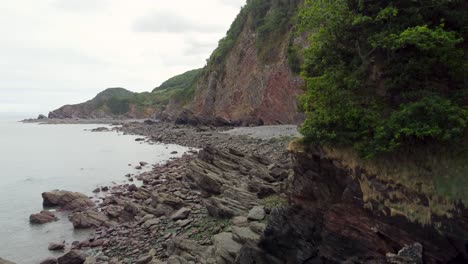 drone aéreo ascendente de acantilados costeros dramáticos con mar y árboles woody bay north devon uk 4k