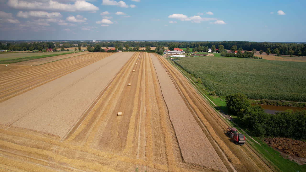 Vast agriculture land with harvesting activity by tractor in progress