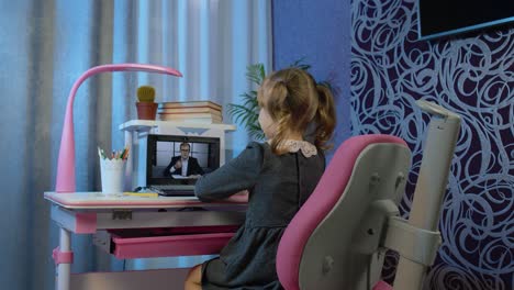 Child-girl-pupil-studying-homework-with-man-teacher-on-laptop-computer-during-online-lessons-at-home