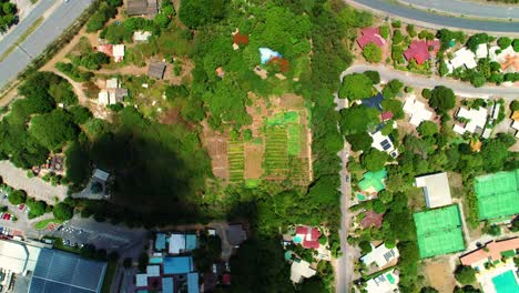 drone top down static shot above farm field surrounded by homes and development, cloud shadow passes over