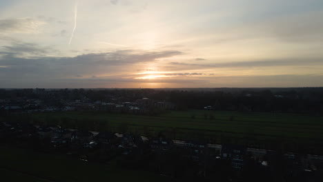 Jib-up-over-row-of-houses-near-a-small,-rural-town-at-sunset